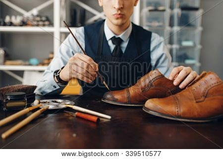 Bootmaker with brush tints shoes, footwear repair