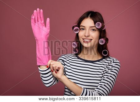 A Smiling Girl With Blue Eyes And Perfect Skin Looks At The Camera And Puts On A Rubber Pink Glove F