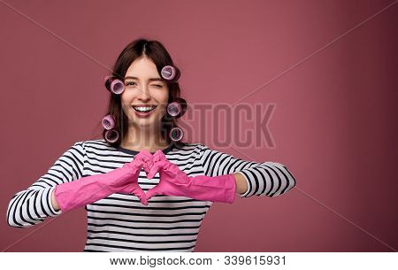 A Cute Girl With Dark Hair And Blue Eyes In A Striped Sweater And Pink Rubber Gloves For Cleaning Sh
