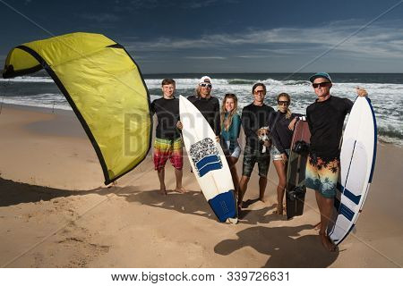 Surfer and kiter boys with beautiful girls group stay on beach