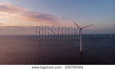 Windmill Park Green Energy During Sunset In The Ocean, Offshore Wind Mill Turbines Netherlands