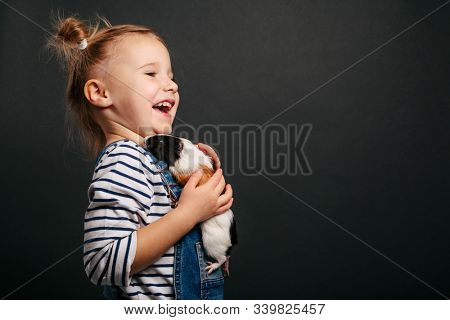 Happy cute boy is having fun played with donuts on black background wall. Bright photo of a boy. Colored donuts