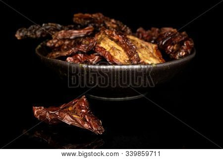 Lot Of Whole Dried Red Tomato Piece Front Focus In Glazed Bowl Isolated On Black Glass