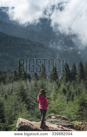 Millenial Girl On A Rock Admiring The Hornisgrinde Mountains Covered By Fir Forest And Clouds, In Th