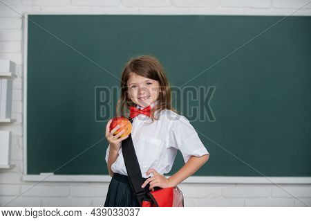 Happy Smiling Preteen Girl, Kid Schoolgirl With Wears Schhol Uniform Holding Backpack On Blackboard 