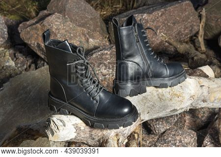 Leather Black Women's Rough Boots With Thick Soles Standing On A Piece Of Wood Against A Background 