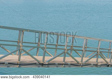 Side View Of Metal Gang Plank Over Ocean Water At Seaport.