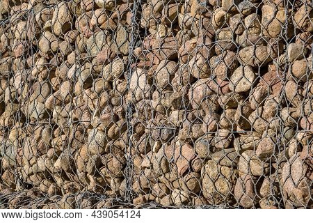 Engineering Structure Made Of Stones Behind Metal Wire Netting To Strengthen The River Bank Near The