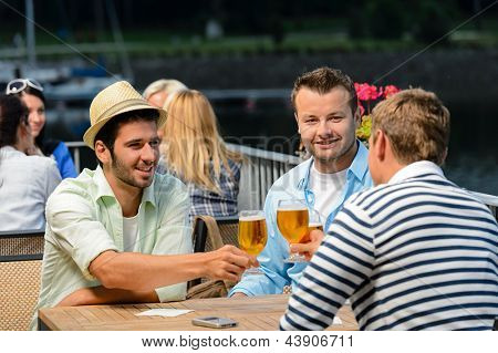 Tre amici maschi rilassarsi bevendo birra serata terrazza ristorante