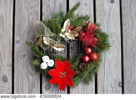 Christmas Wreath Decorated With Red Balls, Lights And Pinecones On Wood Background