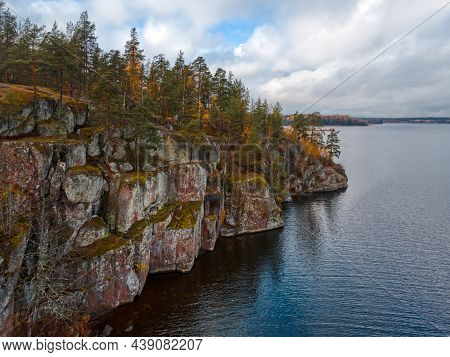 Aerial View Of Rocky Shore With Evergreen Trees And Plants, Lake And Cloudy Sky. Scandinavian Nature