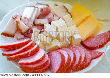 Sausage, Bacon And Cheese Cut Into Slices On A Plate On The Dining Table