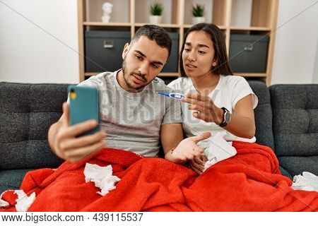 Young latin ill couple having medical teleconsultation using smartphone at home.