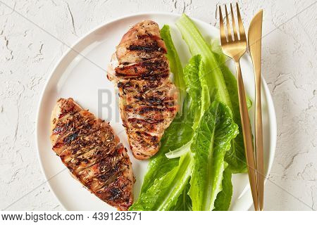Juicy Seared Chicken Breasts With Fresh Romaine Lettuce Leaves On A White Plate With Golden Cutlery 