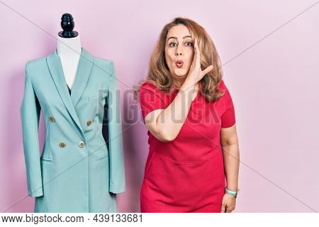Middle age caucasian woman standing by manikin hand on mouth telling secret rumor, whispering malicious talk conversation 