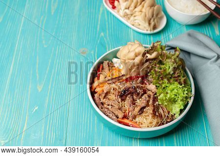 Korean Cuisine. Crystal Noodles With Beef, Vegetables And Mushrooms. Close-up, On A Blue Wooden Back