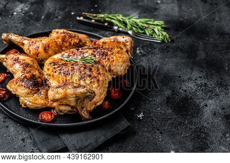 Tobacco Whole Chicken On Plate With Herbs And Tomato. Black Background. Top View. Copy Space