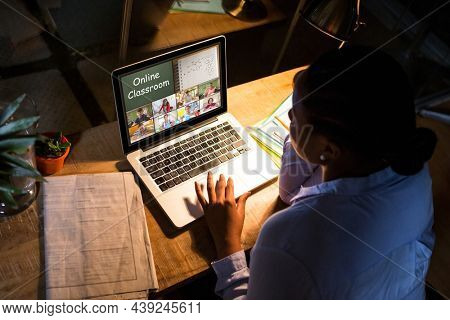 African american woman using laptop for video call, with diverse elementary school pupils on screen. communication technology and online education, digital composite image.