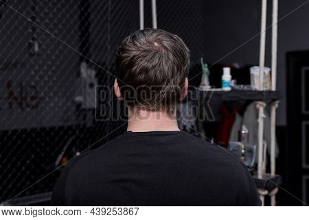 Portrait Occiput Of A Guy Of Caucasian Appearance With Dark Hair In A Black Sweatshirt Against The B