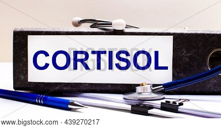 The Desktop Has A Stethoscope, A Blue Pen, And A Gray File Folder With The Text Cortisol. Medical Co