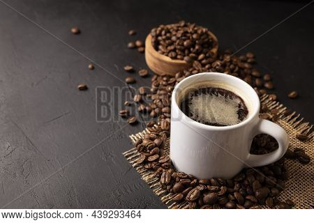 White Lungo Cup With Hot Coffee Drink And Toasted Coffee Beans Scattered On A Rustic Black Table. Co