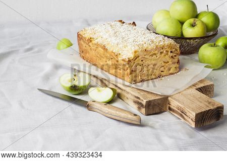 Apple And Coconut Oaf Cake On Wooden Cutting Board And Apples In A Vase