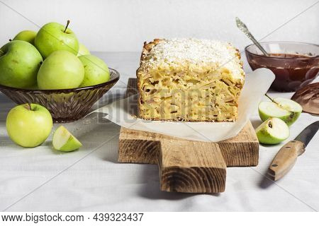 Apple And Coconut Oaf Cake On Wooden Cutting Board And Apples In A Vase
