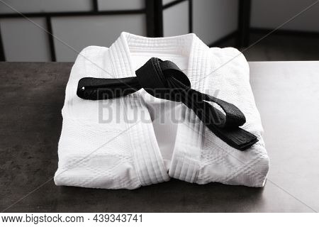 Martial Arts Uniform With Black Belt On Grey Stone Table Indoors