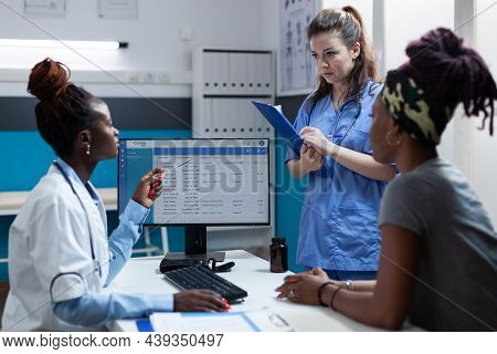 African American Doctor Discussing Healthcare Treatment With Medical Nurse Working In Hospital Offic