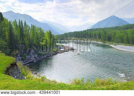 The Bend Of The Riverbed Against The Background Of Mountains Under A Blue Cloudy Sky In Summer. Sibe