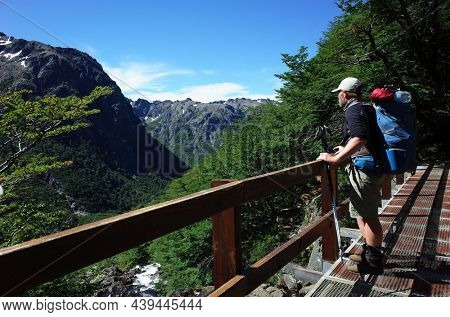 Man with big backpack standing on bridge with green mountain view in Nahuel Huapi national park, Hiking in Patagonia, Argentina