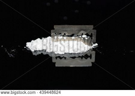 Razor Blade On Drug Powder On Reflection Black Background.copy Space.
