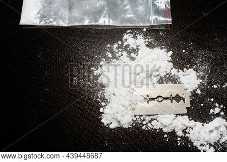 Razor Blade On Drug Powder,cocaine Bag On Reflection Black Background.copy Space.