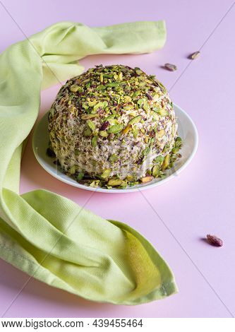 Sesame Halva With Pistachios, Few Scatterred Nuts And Green Linen Napkin On Pink Paper. High Angle V