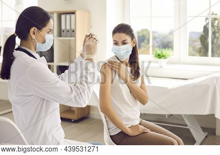Nurse Preparing Syringe To Give Injection Of Vaccine To Female Patient At Vaccination Center.