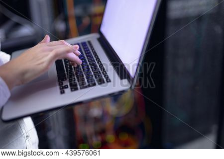Mid section of woman laptop in computer server room. database server management and maintenance concept