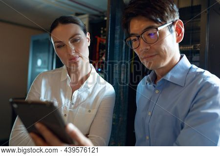 Diverse male and female engineers using digital tablet in computer server room. database server management and maintenance concept