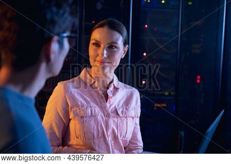Diverse male and female engineers using laptop in computer server room. database server management and maintenance concept
