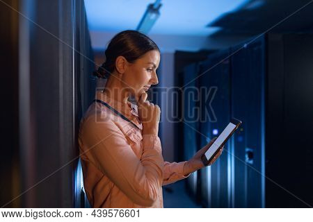 Thoughtful caucasian female engineer using digital tablet in computer server room. database server management and maintenance concept