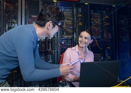 Diverse male and female engineers discussing over a digital tablet in computer server room. database server management and maintenance concept