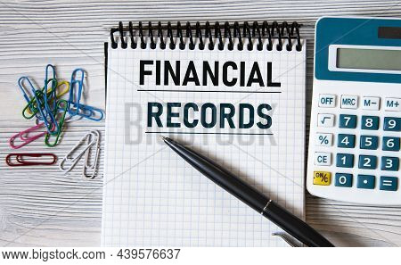Finansial Records - Words On A Notebook On A Light Wooden Background With A Calculator And A Pen. Bu