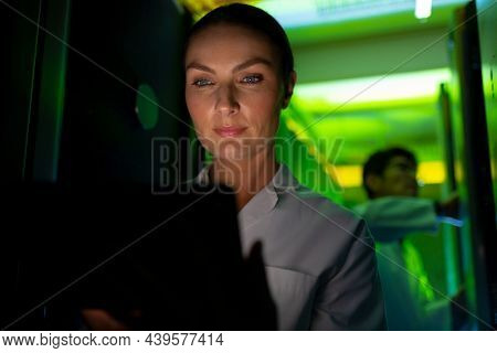 Caucasian female engineer wearing an apron using laptop in computer server room. database server management and maintenance concept