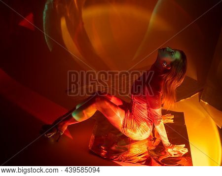 Glamorous Portrait Of A Young Beautiful Blonde In A Stylish Scarlet Short Dress, Sitting On The Floo