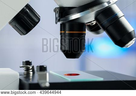 Glass Slide With Sample Of Red Liquid Under Microscope In Laboratory, Closeup