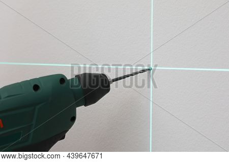 Using Cross Line Laser Level For Accurate Measurement And Drilling Hole In Grey Wall, Closeup