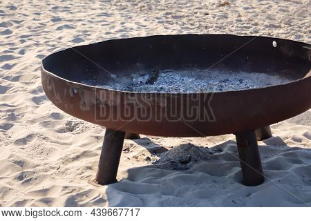 An Iron Fire Bowl For Burning Wood Stands Lonely On The Beach.