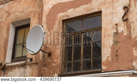 A Fragment Of An Old Building With A Round Satellite Dish On The Wall. Windos On Rear Facade Of Hous