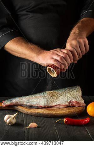 Cook Or Chef Prepares Fresh Fish Bighead Carp Sprinkling Pepper. Preparing To Cook Fish Food. Workin