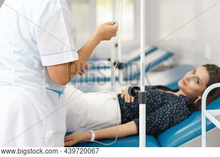 Nurse From Central Asia Ready To Deliver Saline Drip To Patient On Couch.