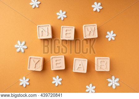 The Inscription New Year On Wooden Cubes. Wooden Cubes With Letters And Snowflakes On An Orange Back